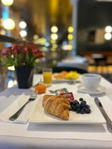 a white plate with a croissant and fruit on a table at Le St-Martin Hotel Centre-ville – Hotel Particulier in Montréal