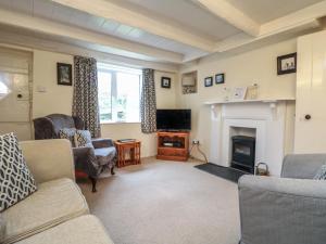 ein Wohnzimmer mit Sofas, Fernseher und Kamin in der Unterkunft 4 Rose Cottages in Looe