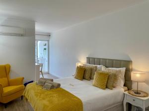 a bedroom with a large bed and a yellow chair at RosaMar apartment sea view and pool in Albufeira