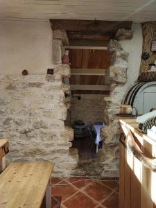 a kitchen with a stone wall and a wooden table at LE DOMAINE DU SENS in Frontenaud