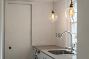 a kitchen with a sink and two pendant lights at Stunning Knightsbridge Townhouse With Patio in London