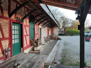 une terrasse couverte d'un bâtiment en briques avec une porte verte dans l'établissement LE DOMAINE DU SENS, à Frontenaud