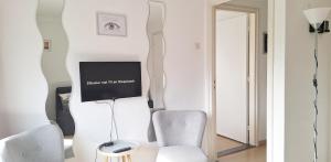 a living room with two chairs and a tv on a wall at B&B Koningsbosch in Koningsbosch