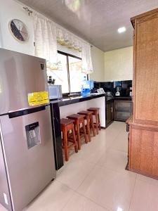 a kitchen with a stainless steel refrigerator and wooden stools at Oso Perezoso Pool Villa in Puerto Viejo