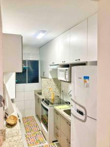 a kitchen with white cabinets and a white refrigerator at Lindo Apartamento na praia de Ponta de Campina in Cabedelo