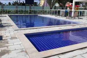 a swimming pool with blue tiles on the ground at Lindo Apartamento na praia de Ponta de Campina in Cabedelo
