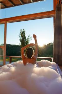a man laying in a cloud shaped bath tub in front of a window at Hospedaria Refugio do Invernador in Urubici
