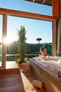 a woman in a tub in a room with a window at Hospedaria Refugio do Invernador in Urubici