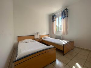 two beds in a room with a window at Villa Giens - Plage à pied -9 couchages in Hyères