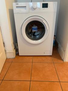 eine weiße Waschmaschine auf einem Fliesenboden in der Unterkunft 4 Bedroom Holiday House in lenton in Nottingham