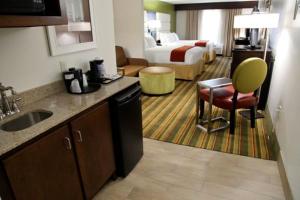 a hotel room with a kitchen and a bedroom at Holiday Inn Express & Suites - Huntsville Airport, an IHG Hotel in Madison