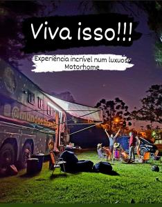 a group of people standing around a bus in a field at Experiência num Luxuoso Motorhome in São Roque