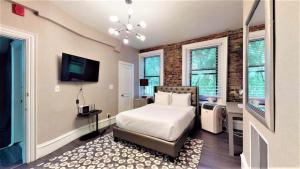 a bedroom with a bed and a tv and windows at Premier Suites Bay Village in Boston