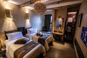 a bedroom with two beds and a mirror at Hotel Xaluca Dades in Boumalne