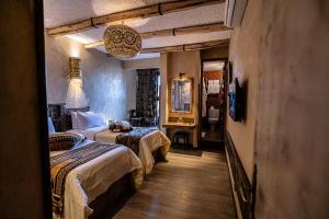 a hotel room with two beds and a mirror at Hotel Xaluca Dades in Boumalne