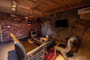 a living room with a stone wall with a table and chairs at Hotel Xaluca Dades in Boumalne