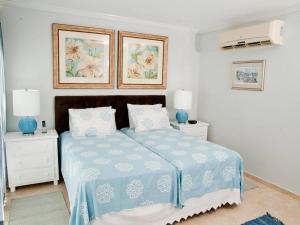 a white bedroom with a blue bed with two night stands at 117 Sapphire Beach Condo in Christ Church +10 photos