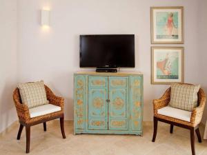 a tv sitting on top of a dresser with two chairs at 117 Sapphire Beach Condo in Christ Church