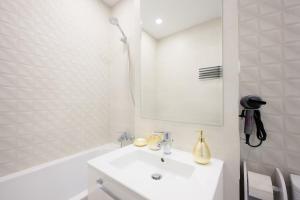 een witte badkamer met een wastafel en een bad bij Charming Hideaway Inspired by El Profesor's Intrigue in Boekarest