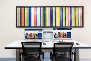 a desk with two computer monitors on top of it at Holiday Inn Express Hotel & Suites Jacksonville - Mayport / Beach, an IHG Hotel in Jacksonville