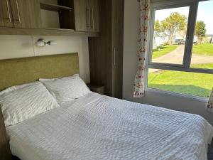 a bedroom with a white bed and a window at D34 Steeple Bay Caravan Site in Chelmsford