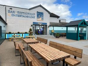 a group of wooden benches outside of a restaurant at D34 Steeple Bay Caravan Site in Chelmsford