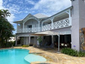 a house with a swimming pool in front of it at Villa Les Jacarandas in Les Avirons
