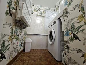a washing machine in a bathroom with floral wallpaper at Logis des Palmiers YourHostHelper in Gruissan