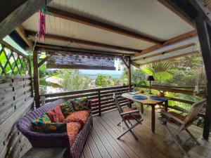 un porche cubierto con sofá y mesa en Studio Bwa Banbou dans Villa Fleurs des Iles, en Le Vauclin