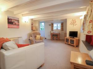 a living room with a couch and a television at 1 Rose Cottages in Looe