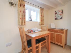 a kitchen with a wooden table and chairs and a window at 1 Rose Cottages in Looe