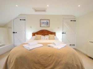 a bedroom with a large bed with two white towels at 1 Rose Cottages in Looe