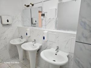 ein weißes Badezimmer mit zwei Waschbecken und Spiegeln in der Unterkunft Rest Hostel Airport Modlin in Nowy Dwór Mazowiecki