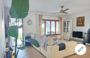 uma sala de estar com um sofá e uma ventoinha de tecto em Casa Isis Garden em Matalascañas