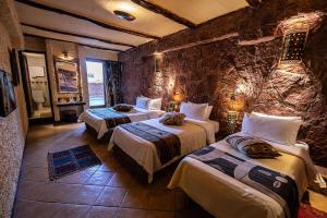 a bedroom with two beds and a stone wall at Hotel Xaluca Dades in Boumalne