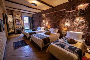 una camera con due letti e un muro di pietra di Hotel Xaluca Dades a Boumalne Dades
