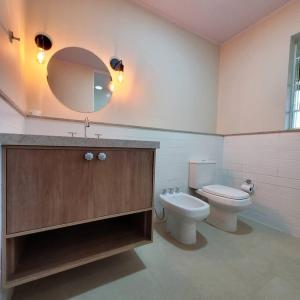 een badkamer met een toilet, een wastafel en een spiegel bij Casa de temporada La Villa - Long Stay - min 7 dias in Campos do Jordão
