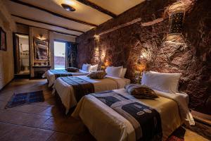two beds in a room with a stone wall at Hotel Xaluca Dades in Boumalne