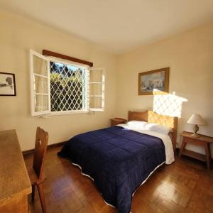 een slaapkamer met een blauw bed en een raam bij Casa de temporada La Villa - Long Stay - min 7 dias in Campos do Jordão