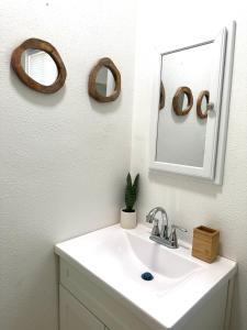 een wastafel in de badkamer met 2 spiegels en een spiegel erover bij Cottage Stay: near LA & OC in Bellflower