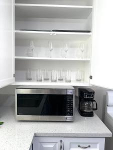 eine Küche mit einer Mikrowelle und Regalen mit Gläsern in der Unterkunft Cottage Stay: near LA & OC in Bellflower