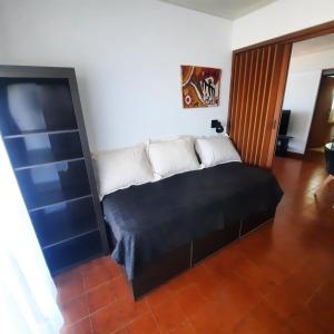Cama en habitación con sofá blanco y negro en Arpon 9 - 5C - Frente al mar 2 dorm. cochera privada en Villa Gesell