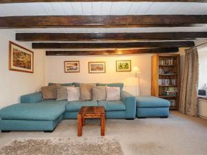 a living room with a blue couch and a table at Larksworthy Cottage in North Tawton