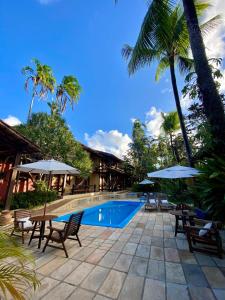 a resort swimming pool with chairs and umbrellas at Hotel Pousada Marambaia in Arraial d'Ajuda