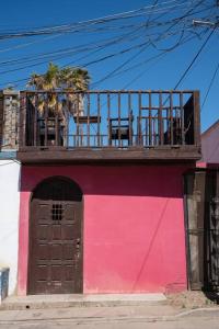 ロサリトにあるBe steps away from the beach - Downtown Rosaritoのピンクの建物で、バルコニーが付いています。