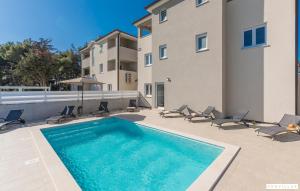 a swimming pool with chairs and a building at Oliva in Premantura