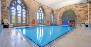 a large swimming pool with blue water in a building at Monastery apartment with Loch Ness view in Fort Augustus