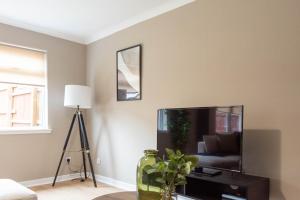 a living room with a flat screen tv and a lamp at Grove House in North Queensferry