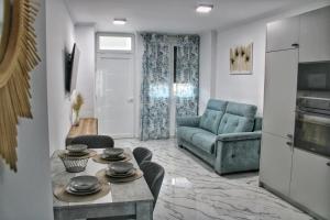 Una sala de estar con un sofá azul y una mesa. en Calpe apartamento nuevo 1a línea playa piscina, en Calpe