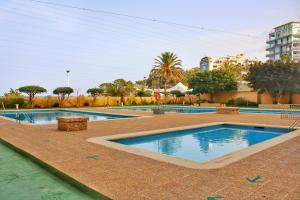 a swimming pool in a resort with trees and buildings at Calpe apartamento nuevo 1a línea playa piscina in Calpe